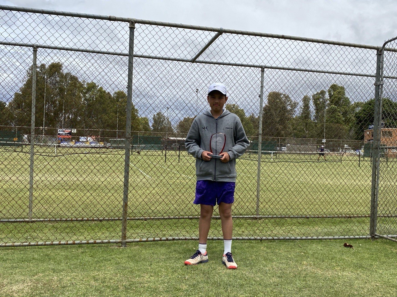 Tianqi as a child holding a trophy at the tennis courts