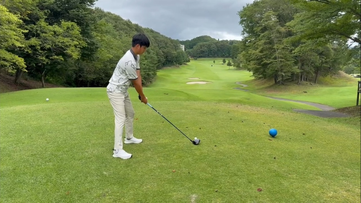 Tianqi Luo preparing to tee off on a tree-lined golf course